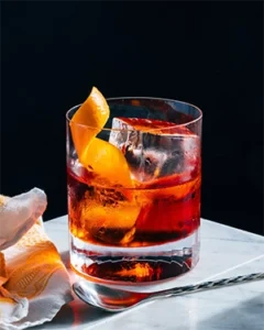 Класичний коктейль Негроні (Negroni) — червоний аперитив у склянці рокс з апельсиновою цедрою