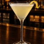 Коктейль Бузиновий Мартіні (Elderflower Martini) у келиху для мартіні з твістом лимона на барній стійці