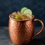 Коктейль Єгермейстер Мул (Jägermeister Mule) у мідному кухлі з льодом, лаймом і кружальцями огірка