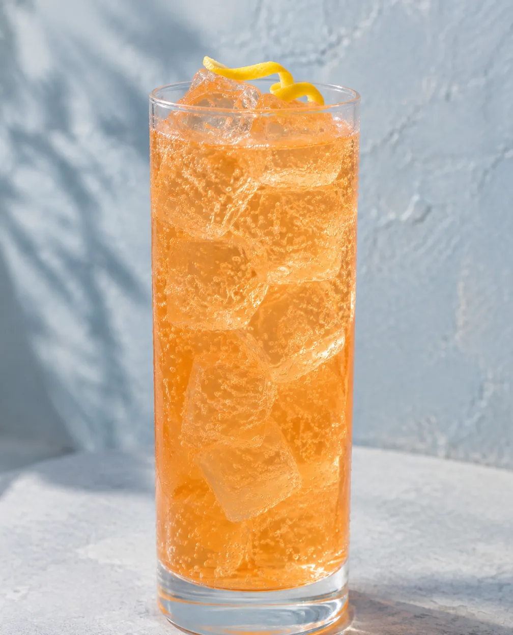 Коктейль Єгермейстер Оранж зі спрайтом (Jägermeister Orange Lemon-Lime Soda) у хайболі з льодом і лимонною цедрою