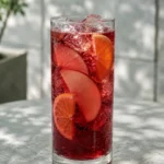 Коктейль Безалкогольна сангрія (Non-Alcoholic Sangria) у високому келиху з часточками яблука та скибочками апельсина