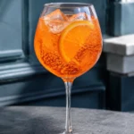 Коктейль Безалкогольний апероль шприц (Virgin Aperol Spritz) у келиху для вина з льодом і скибочкою апельсина